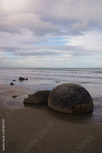 The Moeraki Boulders are unique large round stones lying along of Koekohe Beach in New Zealand