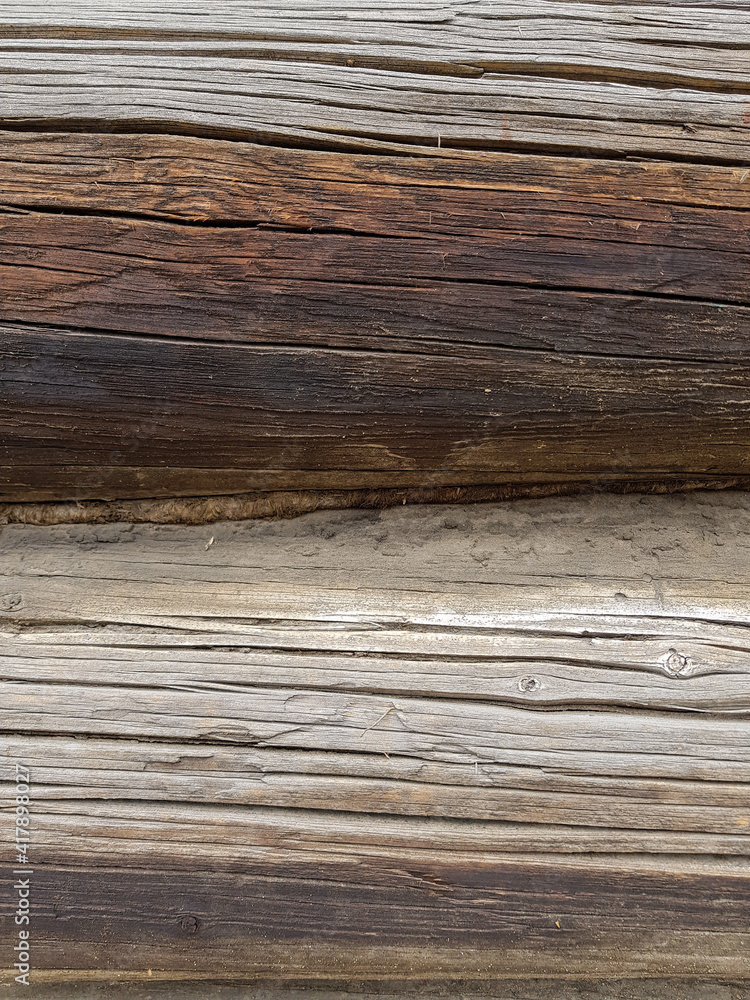 close-up as a background - the texture of an abandoned wooden house, a wall of old wooden blackened beams with slots, horizontally folded, connected by tow. In the countryside, outside the city. close-up as a background - the texture of an abandoned wooden house, a wall of old wooden blackened beams with slots, horizontally folded, connected by tow. In the countryside, outside the city.