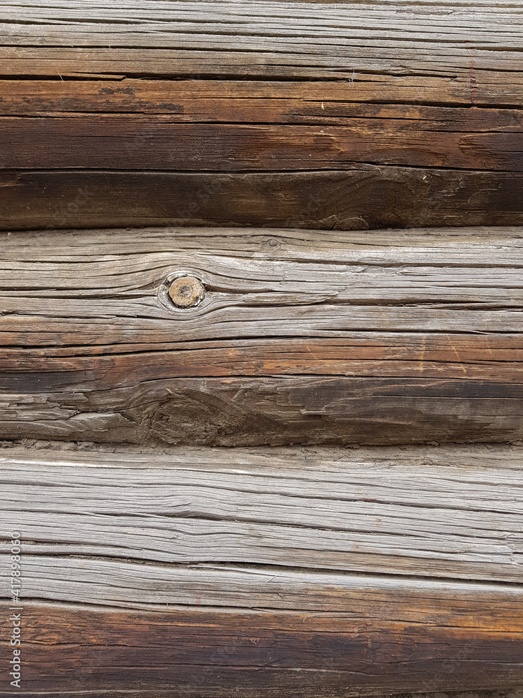 close-up as a background - the texture of an abandoned wooden house, a wall of old wooden blackened beams with slots, horizontally folded, connected by tow. In the countryside, outside the city. close-up as a background - the texture of an abandoned wooden house, a wall of old wooden blackened beams with slots, horizontally folded, connected by tow. In the countryside, outside the city.