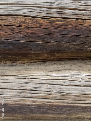 close-up as a background - the texture of an abandoned wooden house, a wall of old wooden blackened beams with slots, horizontally folded, connected by tow. In the countryside, outside the city. 