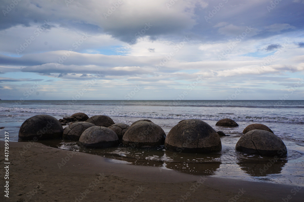 The Moeraki Boulders are unique large round stones lying along of Koekohe Beach in New Zealand