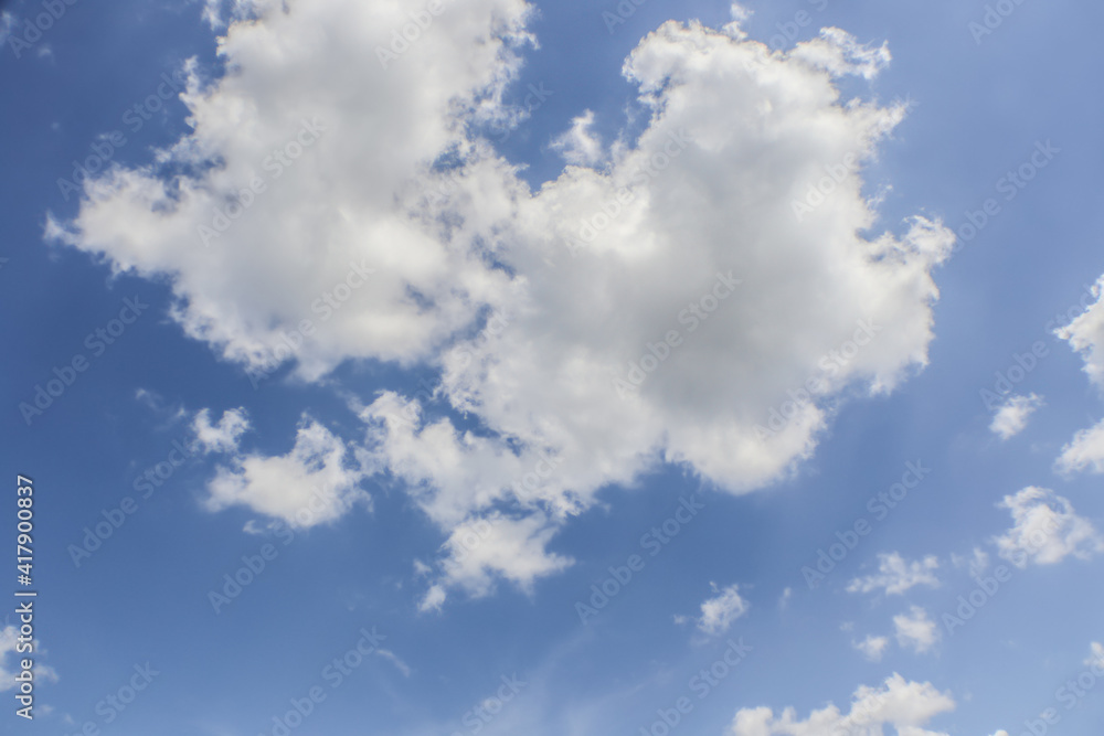 Two big fluffy clouds in blue sky fading lighter on right side. Two big fluffy clouds in blue sky fading lighter on right side.