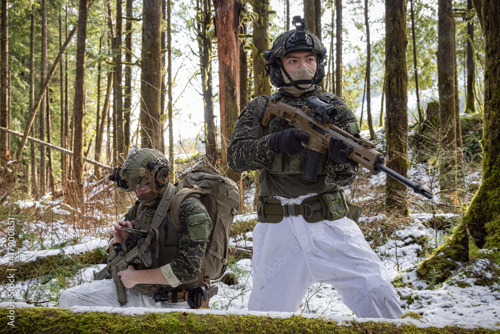 Army Man wearing Tactical Uniform and holding Machine gun in the Outdoor Rain Forest. Winter Warfare. Taken in British Columbia, Canada.
