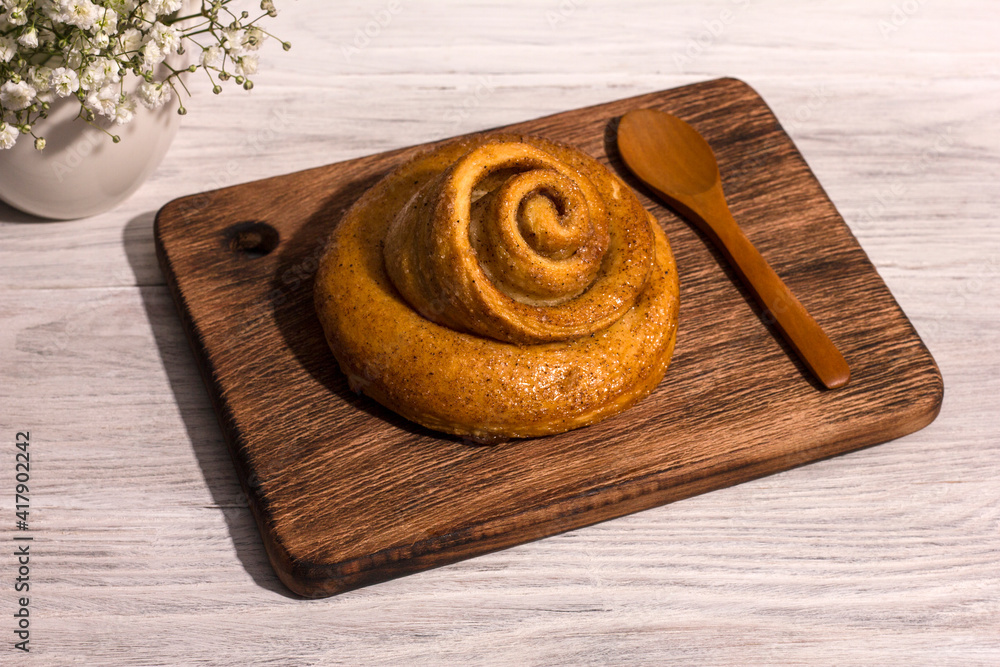 Freshly baked cinnamon bun stuffed with spices and cocoa on a white woden table with a tough shade. Sweet homemade cakes. Freshly baked cinnamon bun stuffed with spices and cocoa on a white woden table with a tough shade. Sweet homemade cakes.