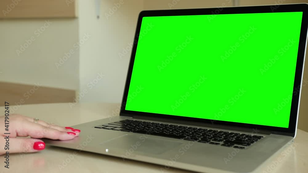 Woman using laptop with keyed blank green screen indoor. Internet communication chat. Chromakey mockup. Computer mock-up display. Over the shoulder camera shot. Woman using laptop with keyed blank green screen indoor. Internet communication chat. Chromakey mockup. Computer mock-up display. Over the shoulder camera shot.