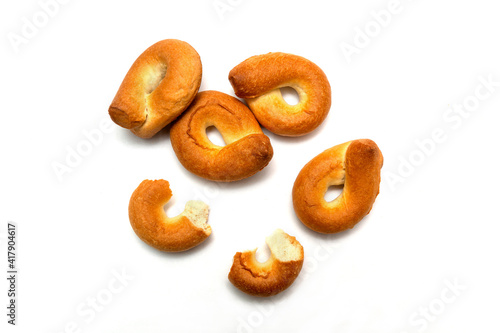 Homemade bagels and their lamellar halves on white isolated background. Traditional dish goes well with tea or coffee