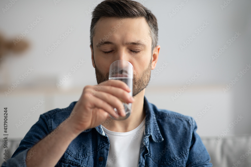 Closeup of middle-aged man drinking water at home Closeup of middle-aged man drinking water at home