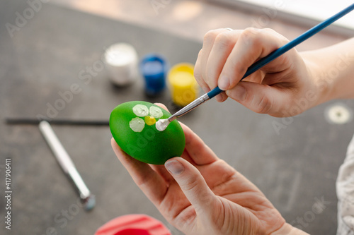 Woman s hands painting with watercolors on the egg to prepare Easter eggs. Homemade decoration for Easter. 