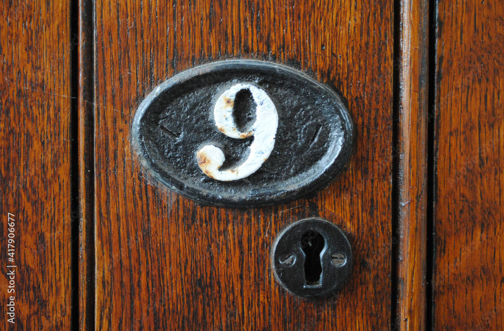 Metal Keyhole and Plaque with Number 9 in Close Up on Old Wooden Door Metal Keyhole and Plaque with Number 9 in Close Up on Old Wooden Door