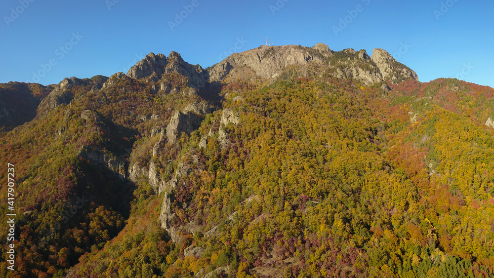 Aerial drone panorama of Cozia National Park in a sunny October day. The mountains are formed from calcareous rocks, so they have spectacular cliff formations, covered by beech forests. Romania.