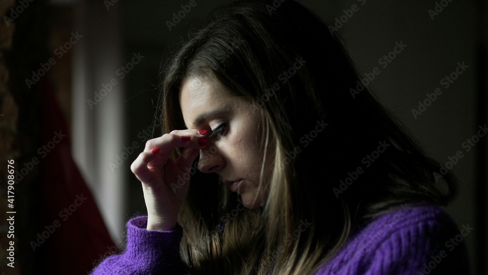 Anxious young woman standing by window concerned with life problems Anxious young woman standing by window concerned with life problems