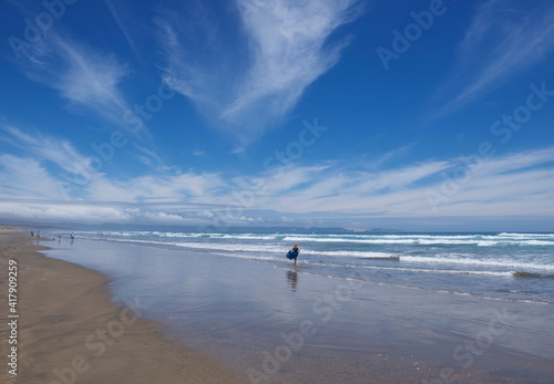 Four people, walking along Ninety Mile Beach, North Island, New Zealand photo