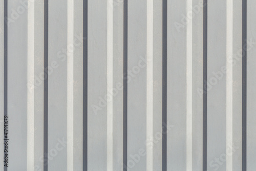Texture of the wall with gray vertical siding panels in strips