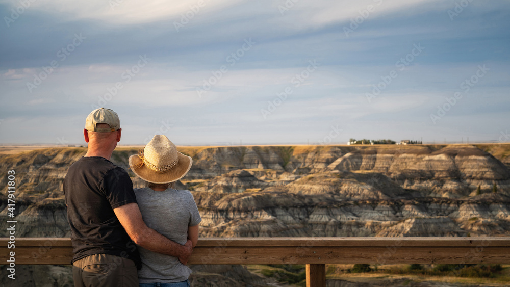 Active senior couple looking at view at Horseshoe Canyon near Drumheller in Alberta, Canada. 
