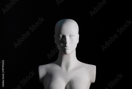 A white female manikin portrait with black background and soft shadows. Art, model and photography concept