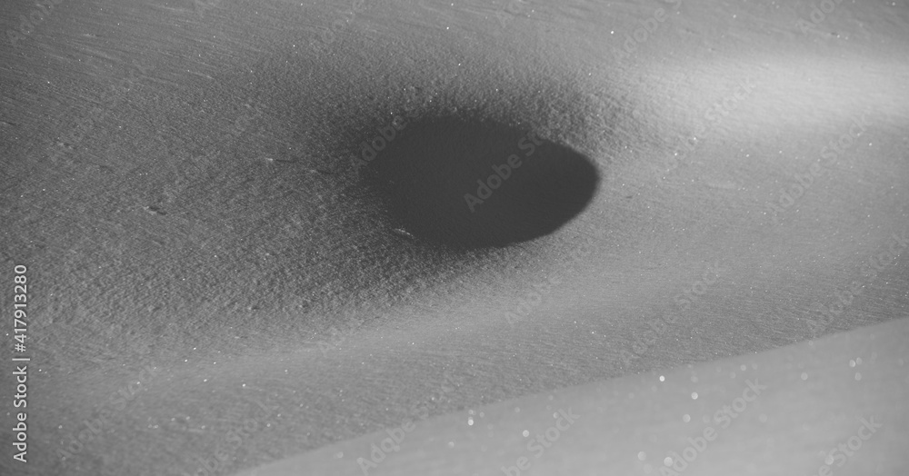 snow scape landscape of swirl in snow shadow cast on snow from sun looking like black hole in textured glistening fresh snowfall on sunny winter day horizontal format background room for type snow scape landscape of swirl in snow shadow cast on snow from sun looking like black hole in textured glistening fresh snowfall on sunny winter day horizontal format background room for type