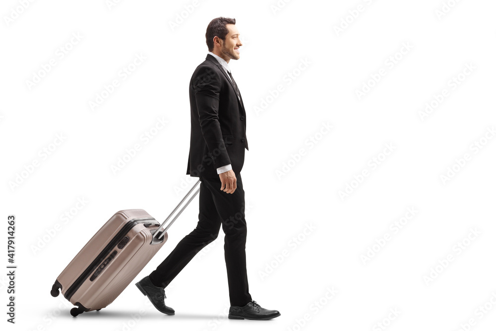 Full length profile shot of a young businessman in a suit walking and carrying a suitcase Full length profile shot of a young businessman in a suit walking and carrying a suitcase