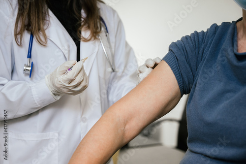 Fototapeta Naklejka Na Ścianę i Meble -  Nurse holds syringe in hand and cleans arm to woman - Doctor in hospital gives vaccine against Coronavirus Covid-19 patient - Medical practitioner vaccinates adult woman in clinic office - Copy space
