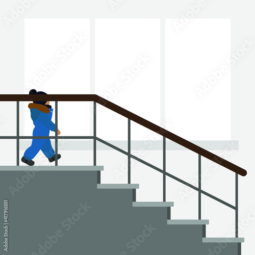 A small child in warm clothes descends the stairs against the background of a wall with a window © Tatyana