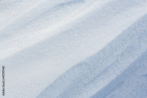Beautiful winter background with snowy ground. Natural snow texture. Wind sculpted patterns on snow surface. © Andrei Stepanov