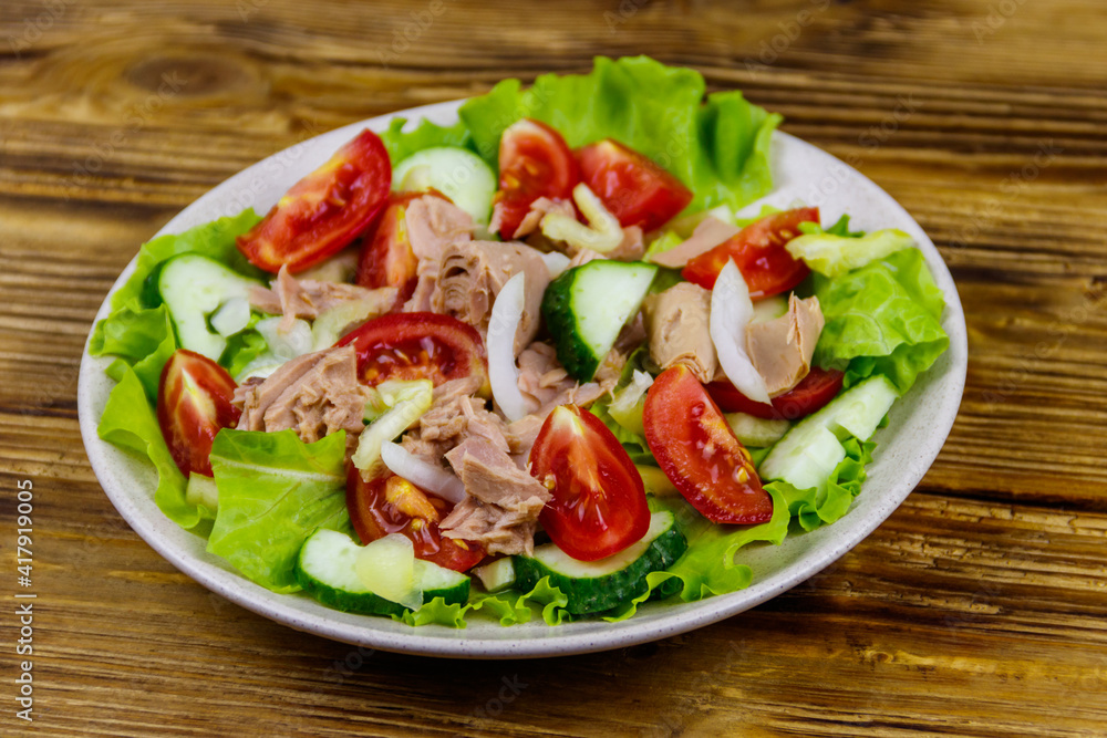 Tasty tuna salad with lettuce and fresh vegetables on wooden table Tasty tuna salad with lettuce and fresh vegetables on wooden table