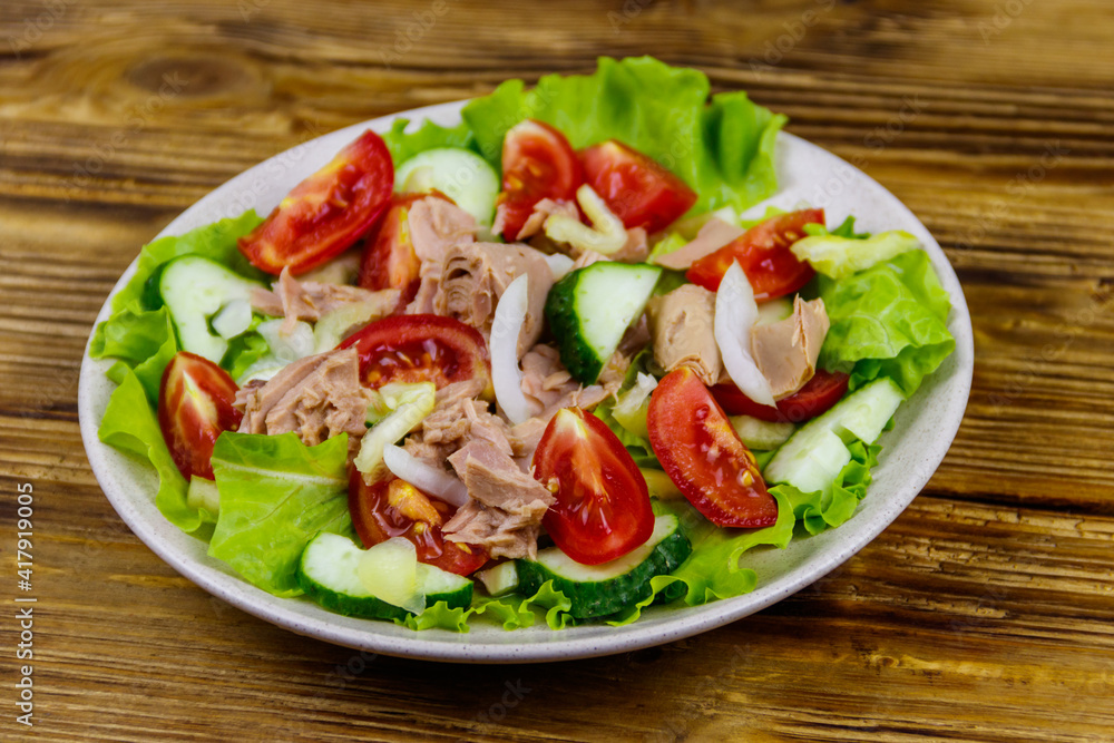 Tasty tuna salad with lettuce and fresh vegetables on wooden table