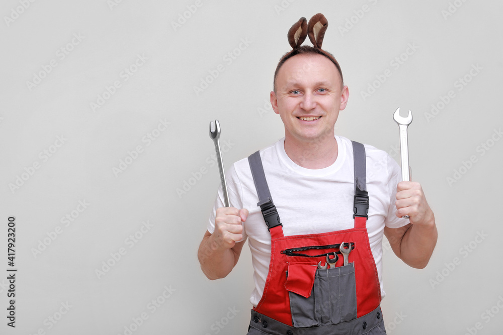 Easter holiday, celebration concept. funny smiling engineer worker or mechanic is wearing rabbit ears on head and holding wrenches white background. celebrating orthodox day Easter holiday, celebration concept. funny smiling engineer worker or mechanic is wearing rabbit ears on head and holding wrenches white background. celebrating orthodox day