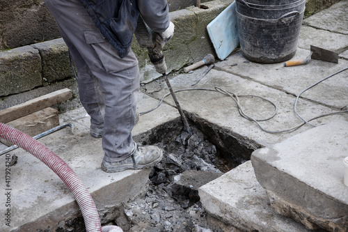 Construction worker with jackhammer working on old paving stone street of historic downtown of Santiago de Compostela, Spain