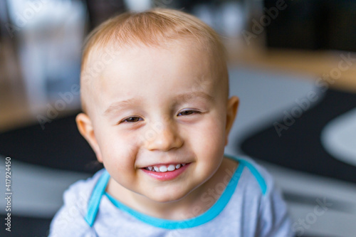 Close up portrait of adorable little boy squinting. Child staying at home looking at the camera with smile.