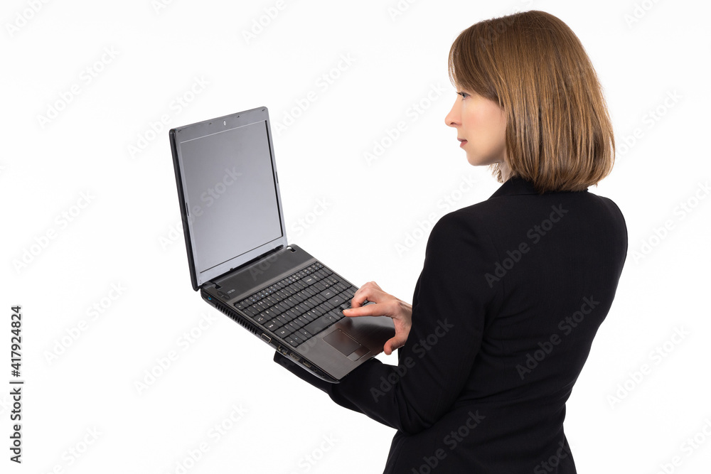 A woman stands and holds a laptop on a white background. Girl with laptop isolated on white. The girl is standing with her back and holding a laptop with a blank screen. Computer screen for text. A woman stands and holds a laptop on a white background. Girl with laptop isolated on white. The girl is standing with her back and holding a laptop with a blank screen. Computer screen for text.