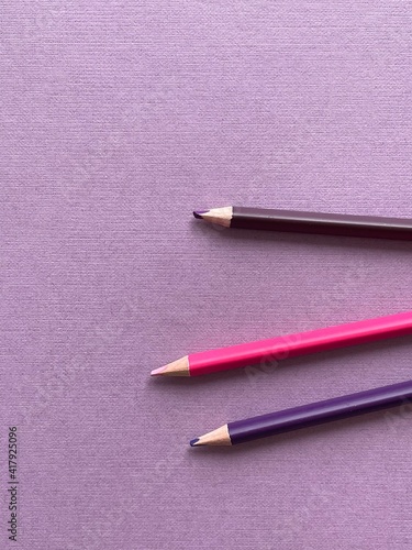 Colored pencils on purple paper album on white table. Artist, art and hobby. Drawing and painting
