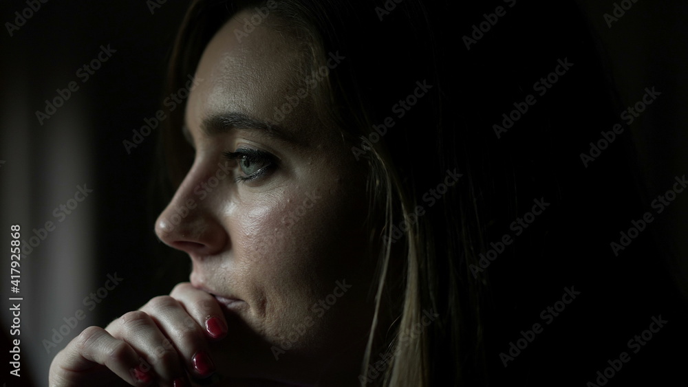 Thoughtful young woman standing by window thinking about life looking outside indoors Thoughtful young woman standing by window thinking about life looking outside indoors