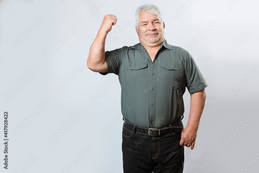 Strong senior man showing his arm muscles. Happy Hispanic elderly man with clenched fists on white background. Strong senior man showing his arm muscles. Happy Hispanic elderly man with clenched fists on white background.