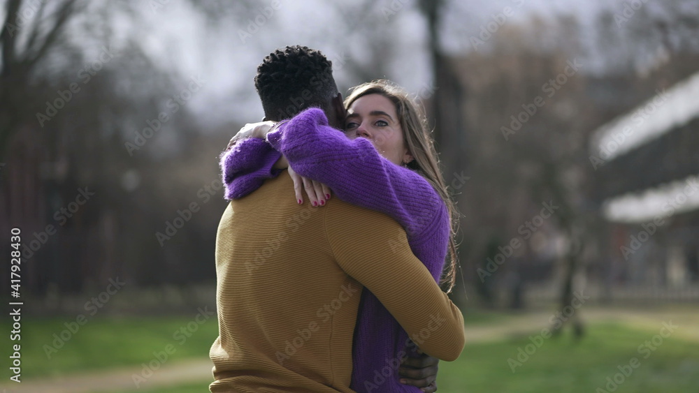 Young interracial couple hugging outside. Empathic embrace standing outside at park