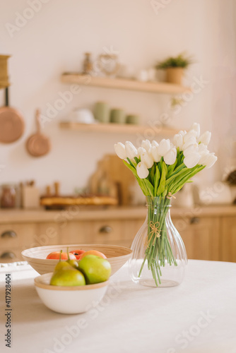 Bouquet of spring flowers in a vase and fruit on the kitchen table. Scandinavian style. Mothers Day. March 8, International Women's Day