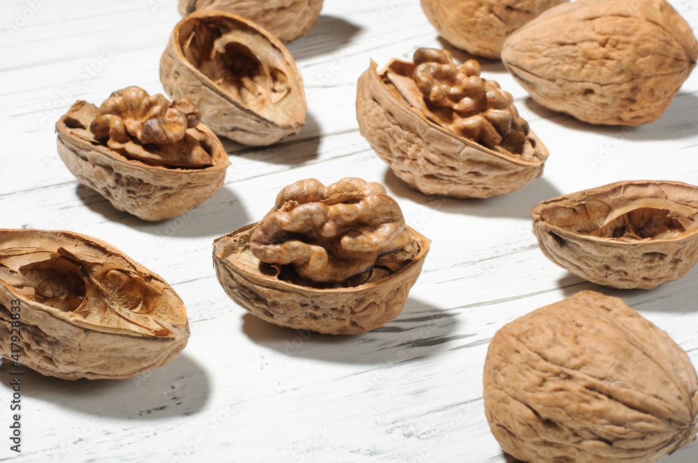 Walnut kernels and nuts in shell on white wooden table