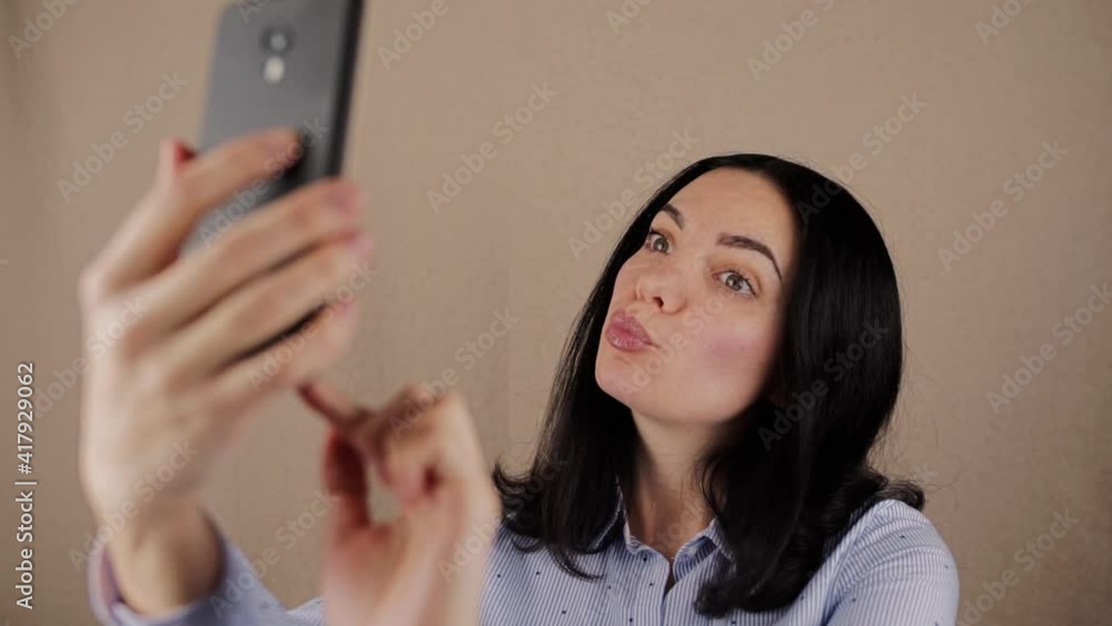 woman with dark hair in a shirt makes a selfie on a mobile phone on the background woman with dark hair in a shirt makes a selfie on a mobile phone on the background