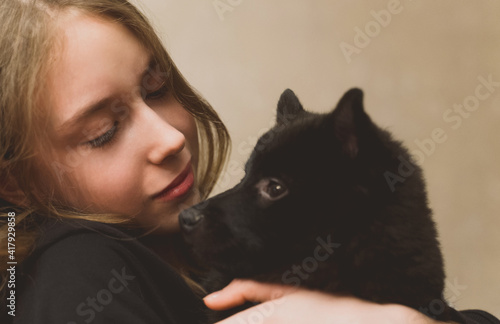 Portrait of tween girl with Schipperke puppy.