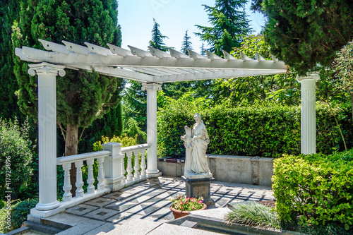 Summer house with old statue of antique goddess. Blooming plants all around. Shot in city park Paradise (sanatorium Ayvazovskoe), Partenit, Crimea