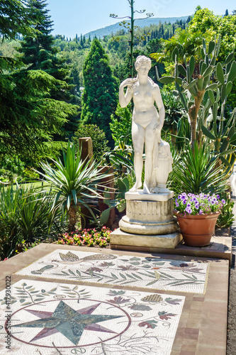 Ancient statue of Greek goddess among flowers and trees. Pavement is decorated with mosaics. Shot in city park Paradise (or Aivazovsky), Partenit, Crimea photo