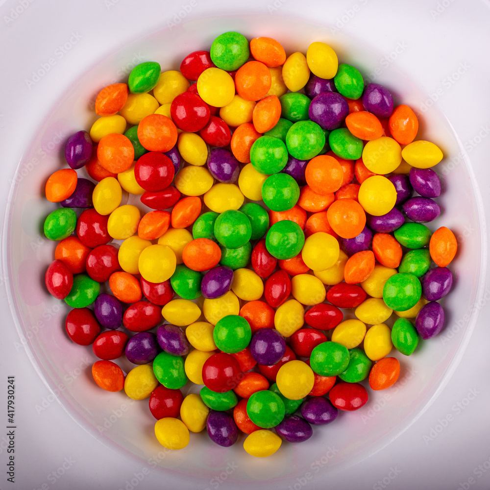 Top view of a pile of colorful shiny Skittles in a white round bowl Top view of a pile of colorful shiny Skittles in a white round bowl