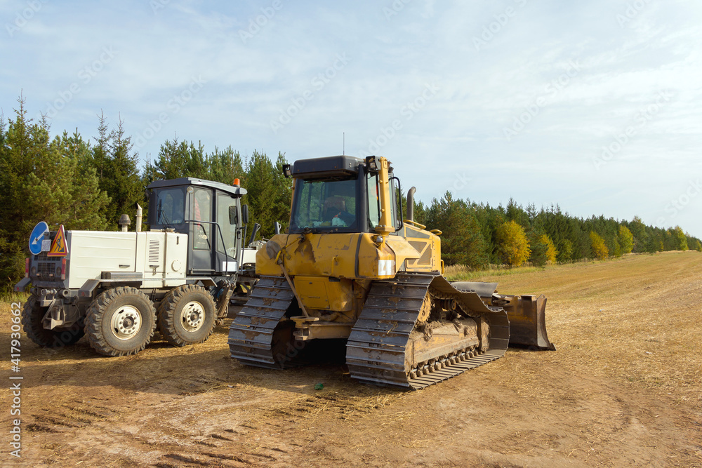 Close-Up View Of Heavy Bulldozer. Construction machinery. Bulldozer on the construction of a new road. Dedicated Construction machinery for handling bulk materials Close-Up View Of Heavy Bulldozer. Construction machinery. Bulldozer on the construction of a new road. Dedicated Construction machinery for handling bulk materials