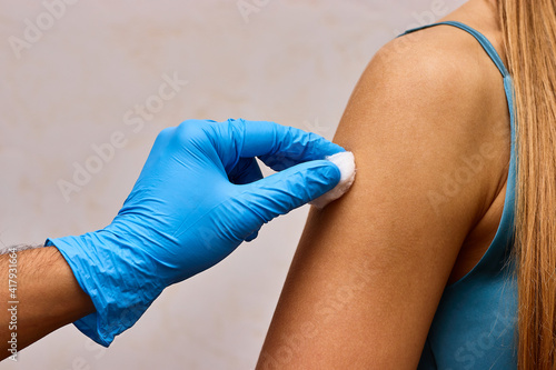 Doctor is desinfecting patien's hand before injection.  Cotton wool with antiseptic in the doctor’s hand.