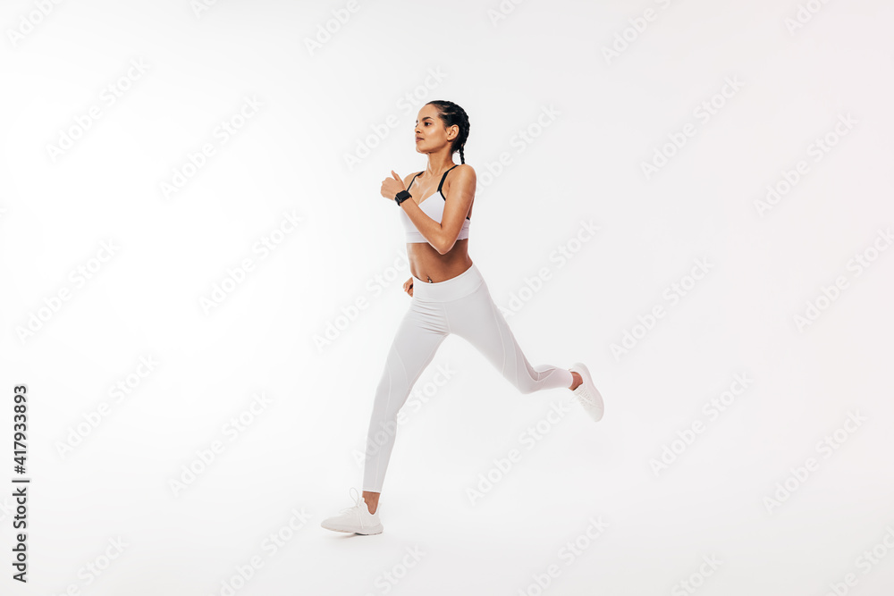 Fitness woman in sportswear running over white background in studio