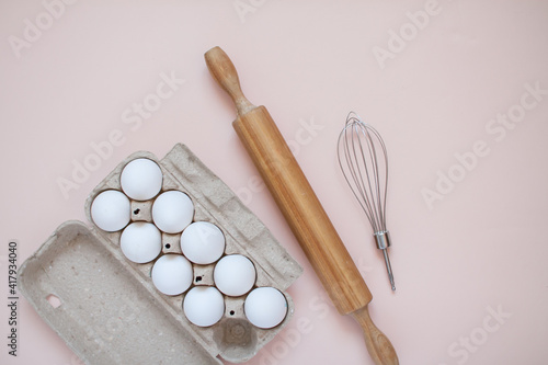 Preparation for baking. Cassette of eggs, rolling pin and whisk on a light background. Kitchen layout. High quality photo