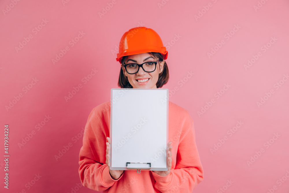 Smiling woman worker builder hold white sign board blank against pink background. Building helmet. Smiling woman worker builder hold white sign board blank against pink background. Building helmet.