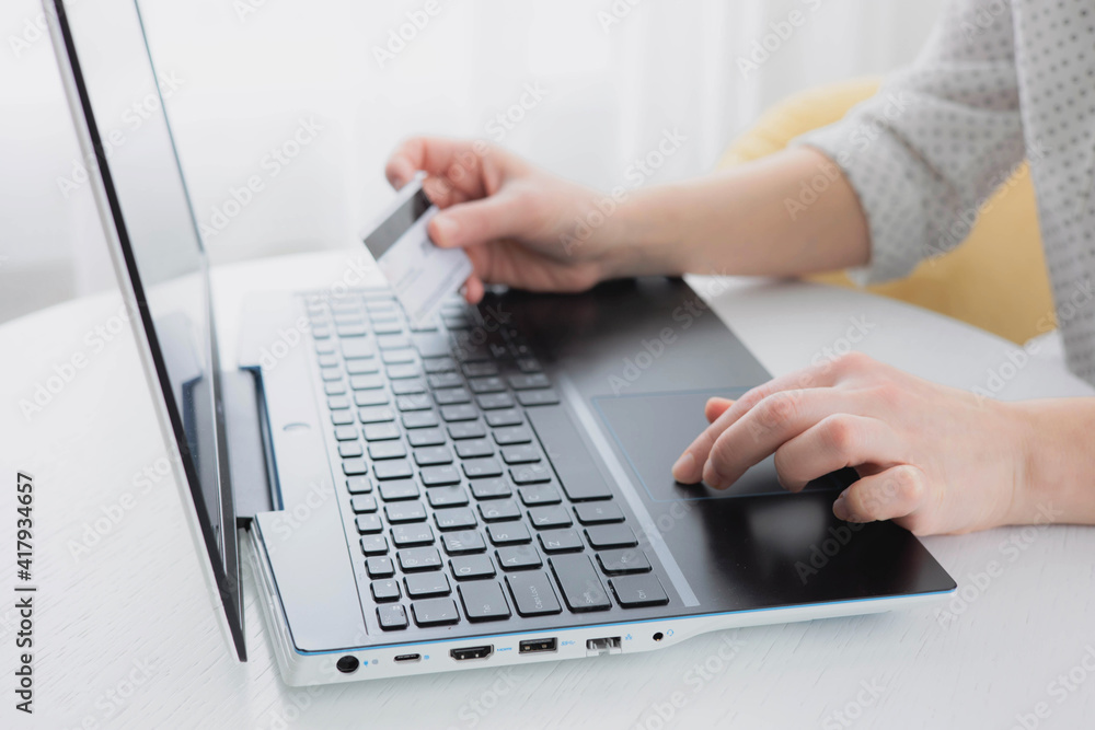 Woman's hands holding credit bank card and using laptop computer at home Online shopping concept Woman's hands holding credit bank card and using laptop computer at home Online shopping concept