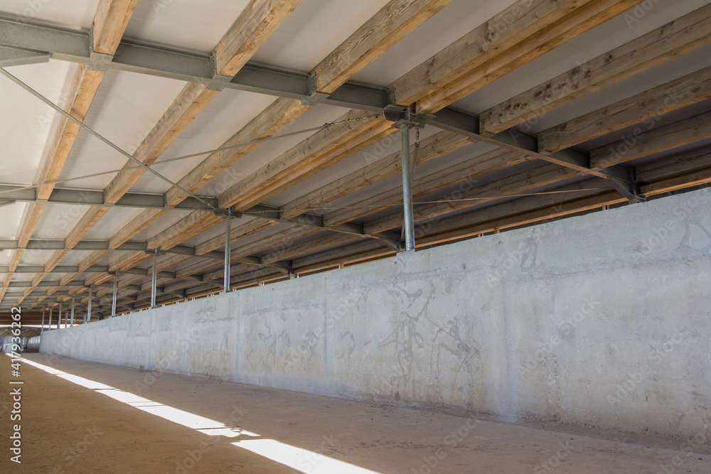 The roof structure of a large hangar consists of a steel frame and timber floor joists. Construction phase of a large complex on a farm The roof structure of a large hangar consists of a steel frame and timber floor joists. Construction phase of a large complex on a farm