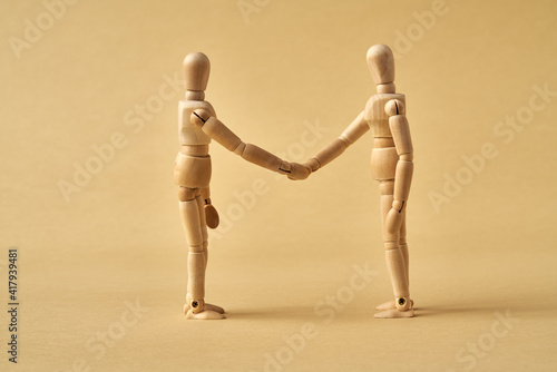 Two wooden figures shaking hands, friendship or agreement concept photo