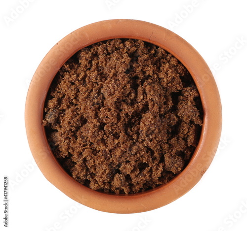 Muscovado sugar in clay bowl isolated on white background, top view